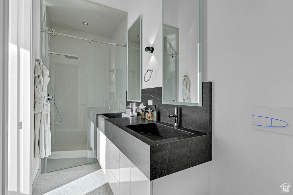 Bathroom with tasteful backsplash, a shower with shower door, and sink