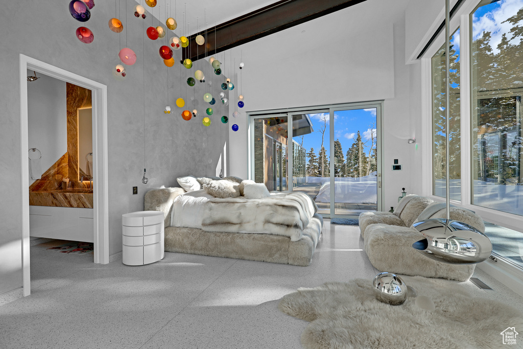 Bedroom with a towering ceiling, access to exterior, and multiple windows