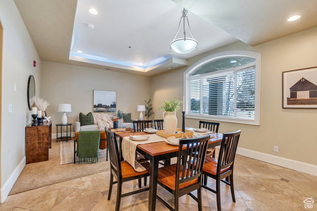 Dining room featuring light tile patterned floors and a raised ceiling