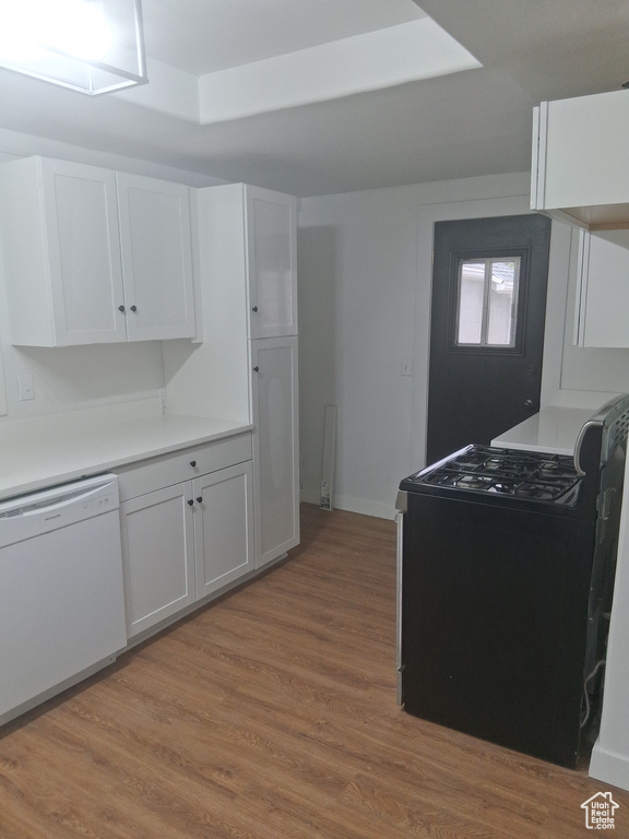 Kitchen with gas range, white dishwasher, white cabinetry, and light wood finished floors
