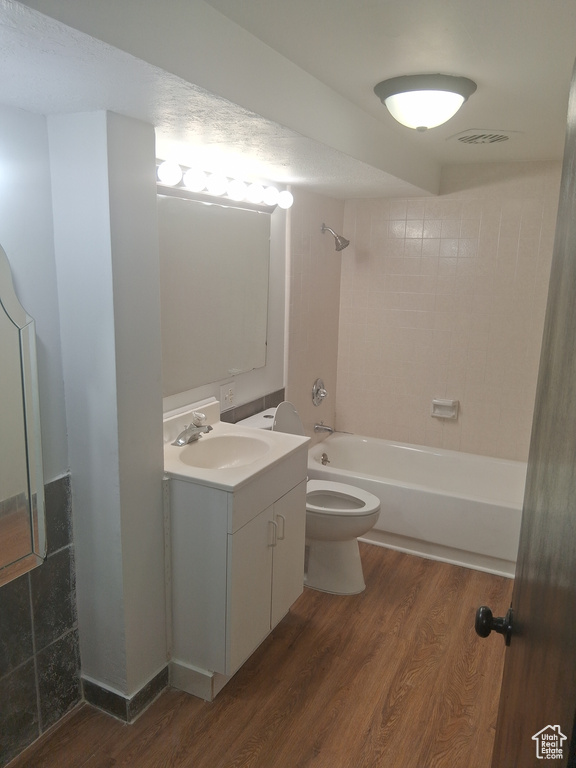 Bathroom with wood finished floors, toilet, tub / shower combination, and vanity