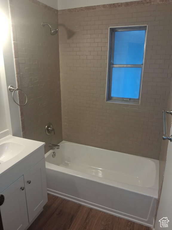 Bathroom with wood finished floors, washtub / shower combination, and vanity