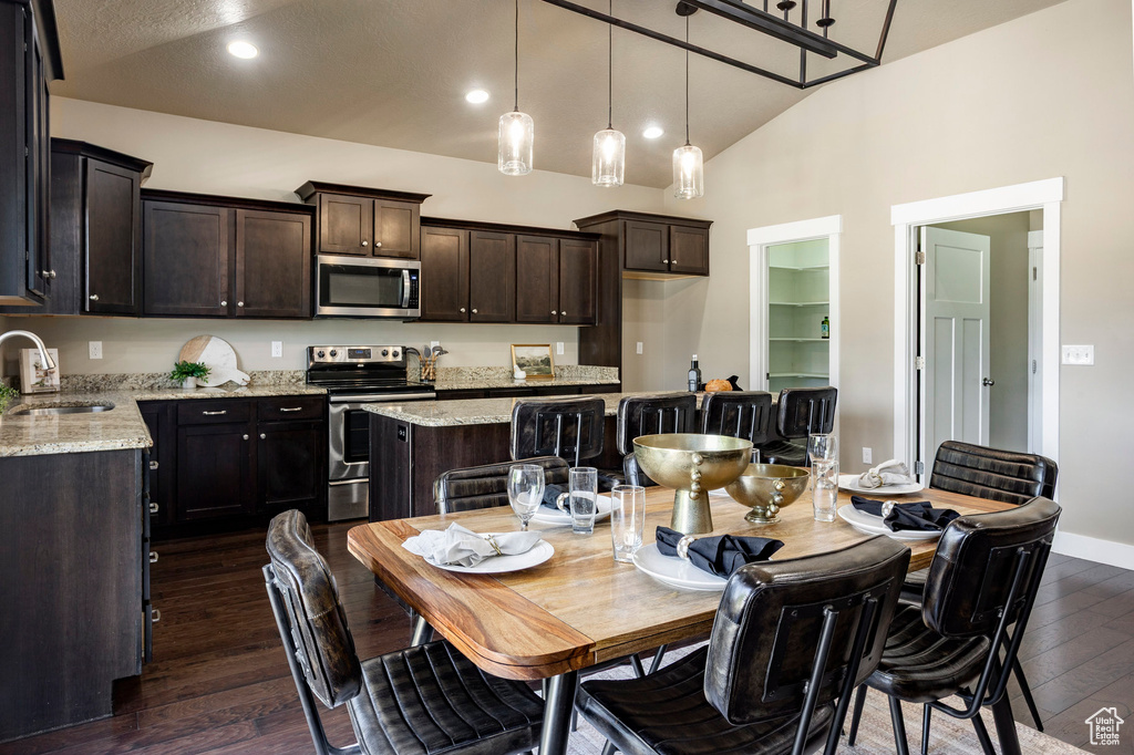 Dining area featuring dark wood finished floors, recessed lighting, baseboards, and high vaulted ceiling
