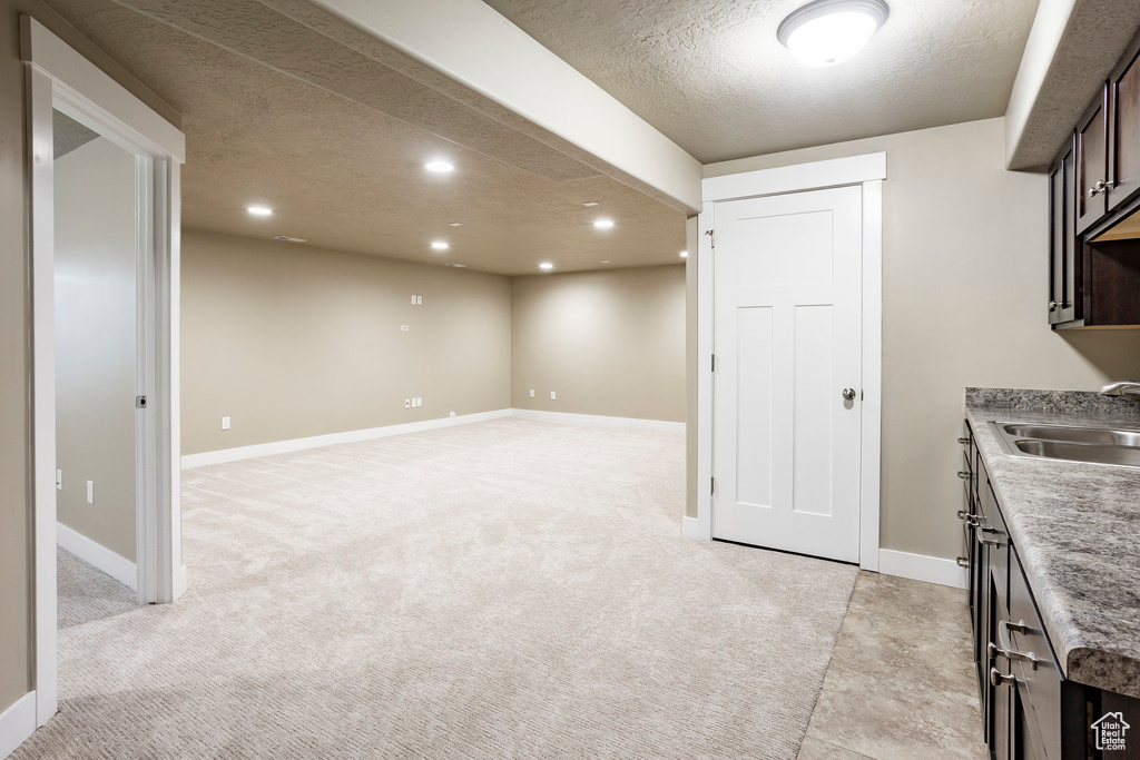 Kitchen with a sink, recessed lighting, a textured ceiling, dark brown cabinets, and baseboards