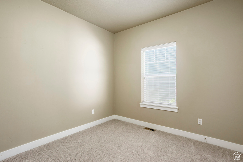 Spare room featuring baseboards and light carpet