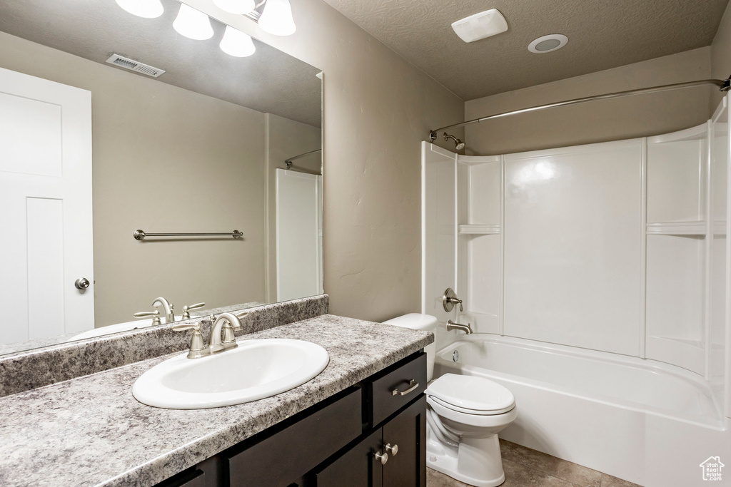 Bathroom with vanity, shower / bath combination, toilet, a textured ceiling, and tile patterned floors