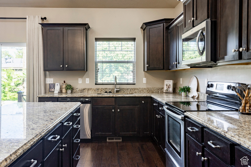 Kitchen with appliances with stainless steel finishes, a sink, dark wood finished floors, and plenty of natural light