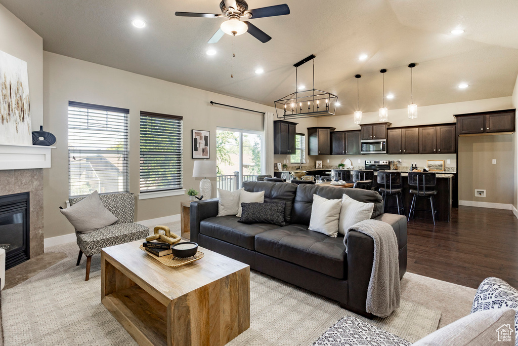 Living room with a ceiling fan, baseboards, recessed lighting, a tile fireplace, and lofted ceiling