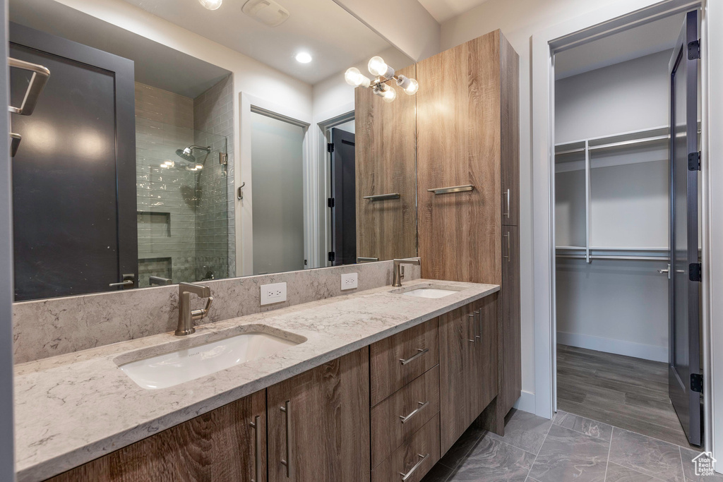 Full bathroom with a stall shower, double vanity, a spacious closet, and marble look tile flooring