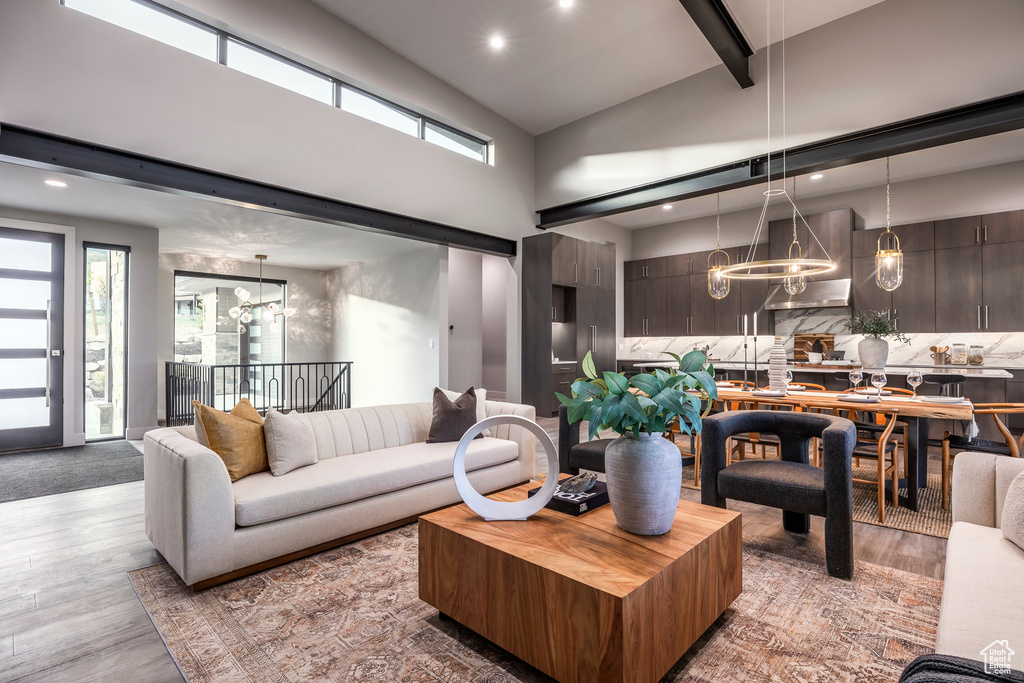 Living room with a chandelier, wood finished floors, plenty of natural light, high vaulted ceiling, and recessed lighting