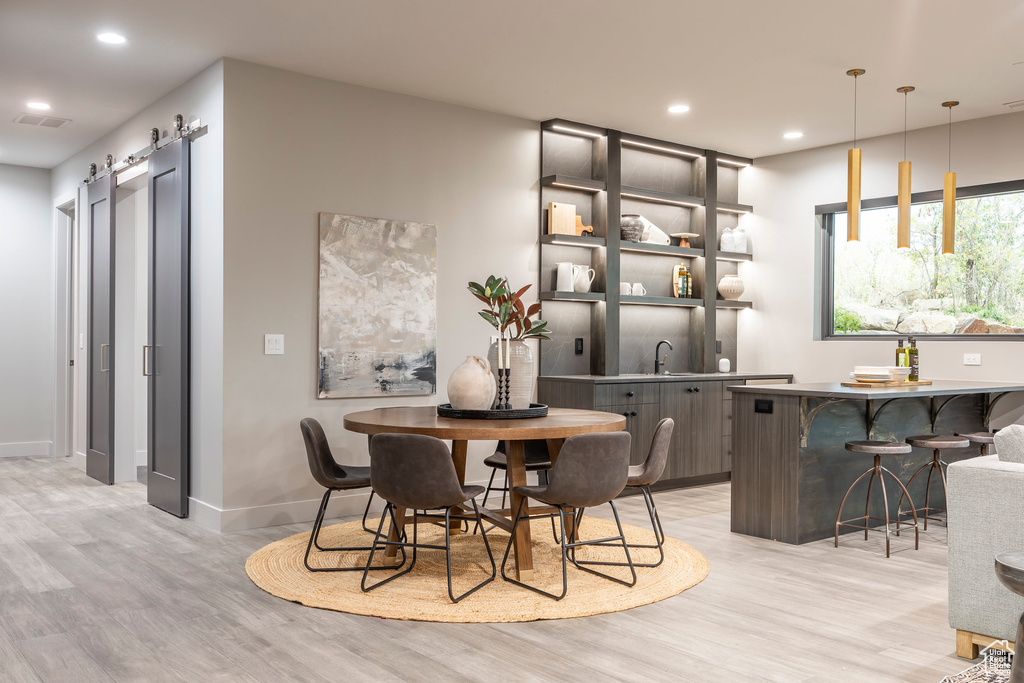 Dining room with light wood-style floors, recessed lighting, baseboards, and a barn door