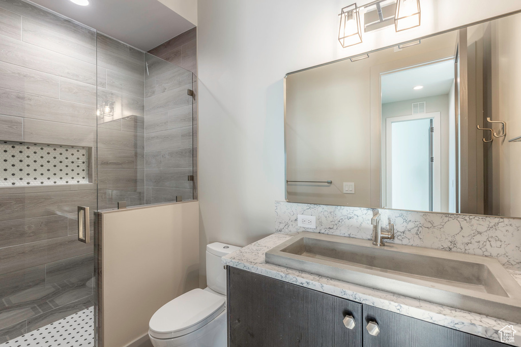 Full bath featuring toilet, a stall shower, and vanity