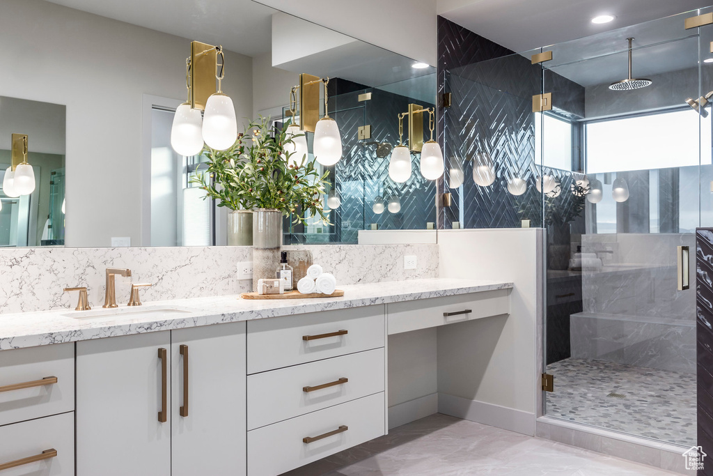 Bathroom featuring a shower stall, double vanity, backsplash, and marble finish flooring
