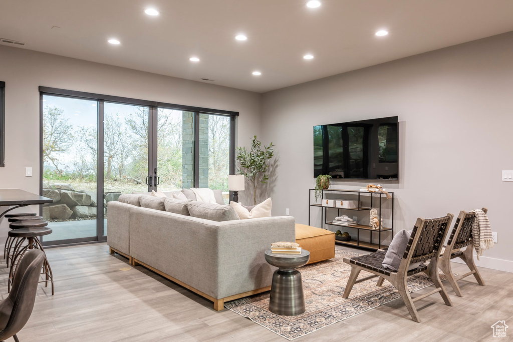 Living room with light wood-style flooring and recessed lighting
