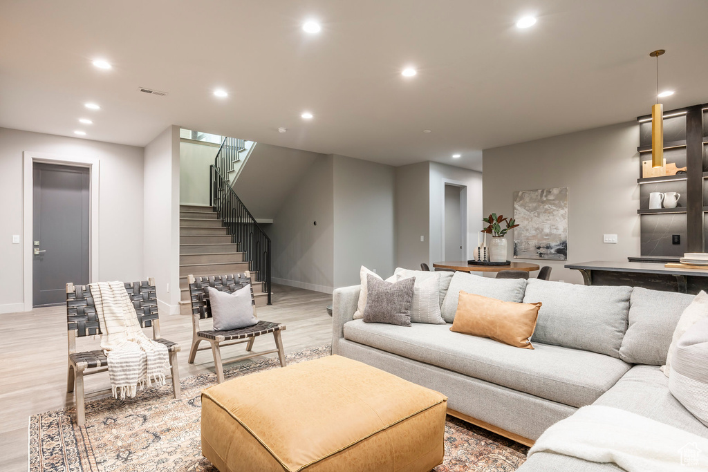 Living room featuring light wood-type flooring, stairway, recessed lighting, and baseboards
