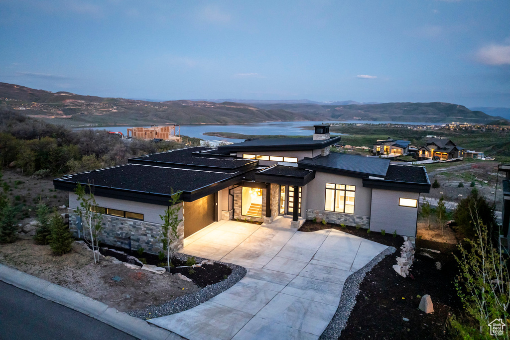 View of front of property featuring stone siding, concrete driveway, a mountain view, and an attached garage