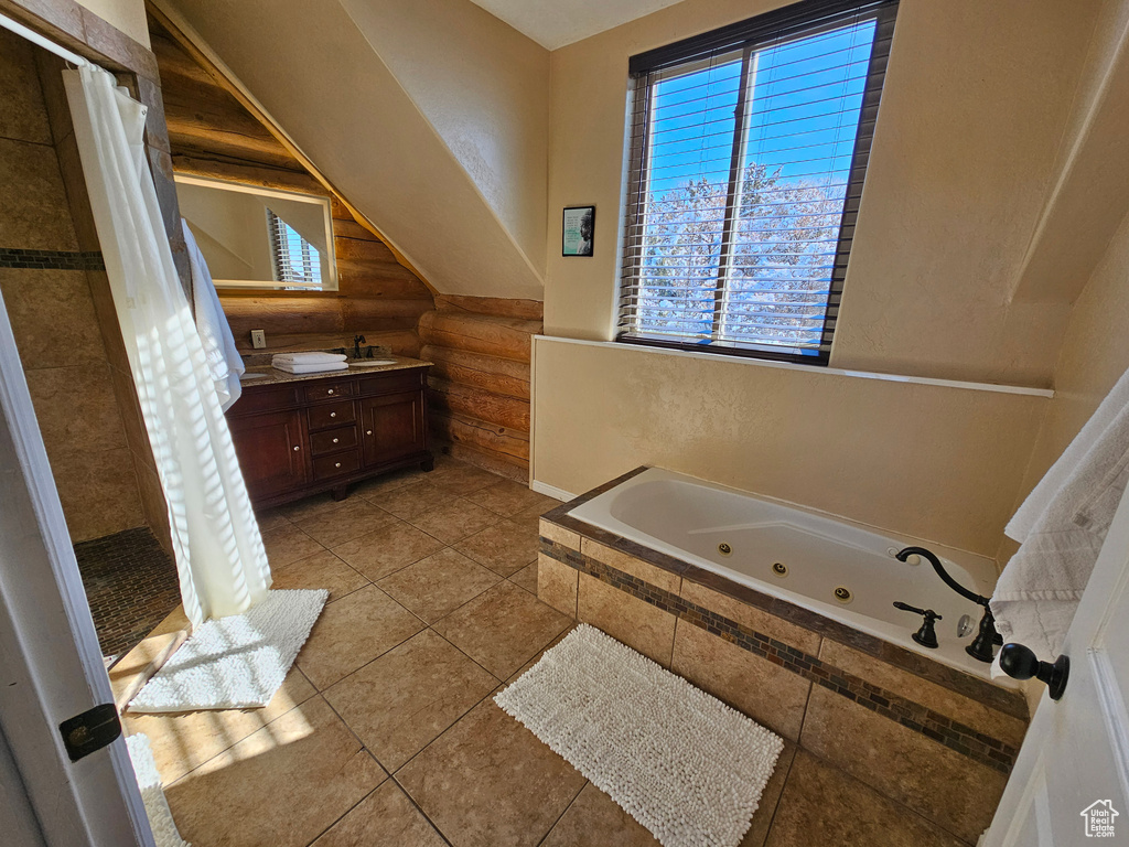 Bathroom with a relaxing tiled tub, vanity, and log walls