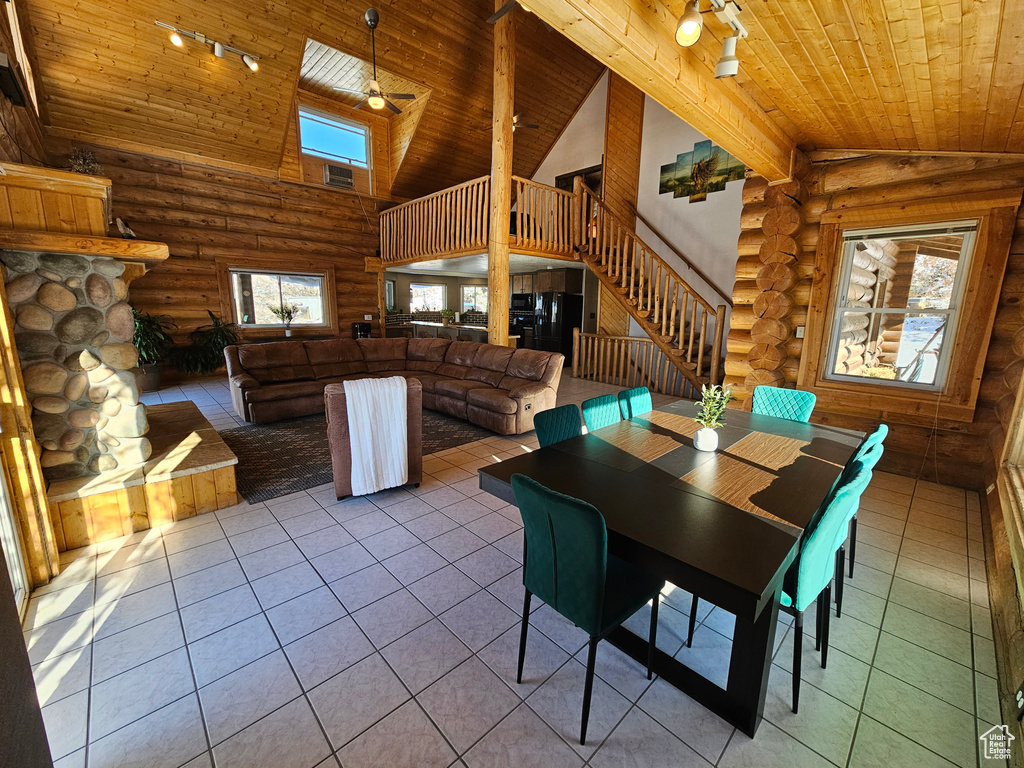 Tiled dining room with beam ceiling, log walls, high vaulted ceiling, and wood ceiling