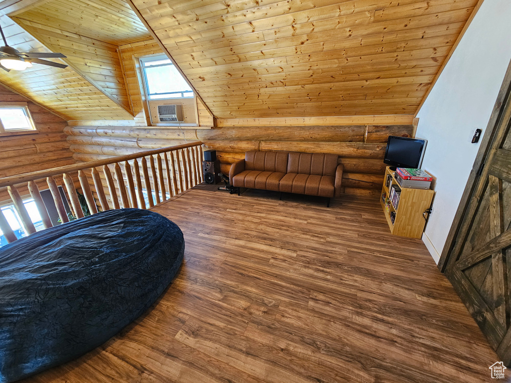 Additional living space with log walls, wooden ceiling, ceiling fan, and hardwood / wood-style flooring