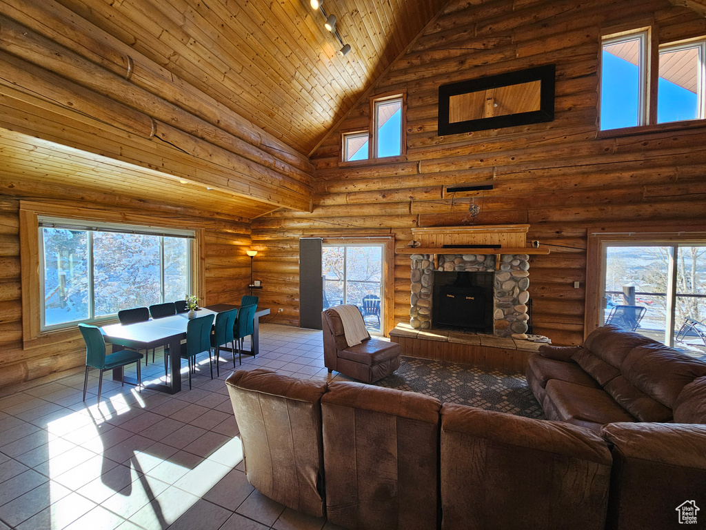 Tiled living room with wooden ceiling, rustic walls, high vaulted ceiling, and a stone fireplace