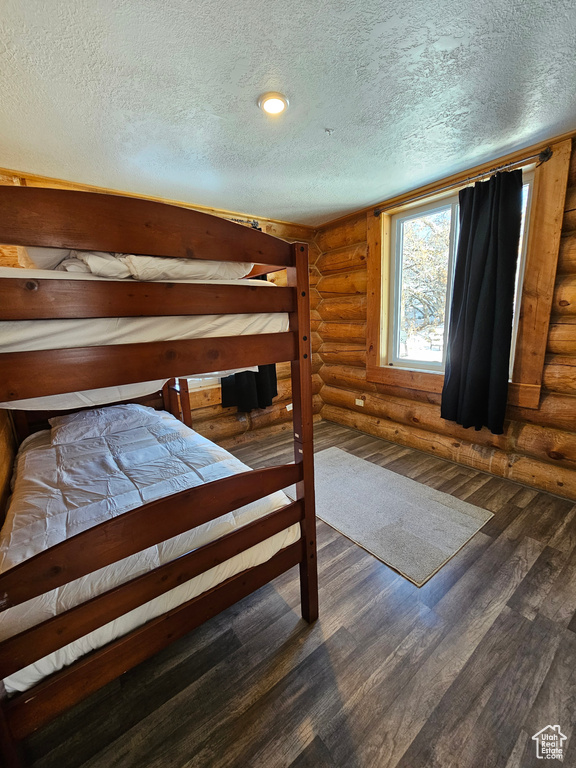 Unfurnished bedroom with dark hardwood / wood-style floors and rustic walls