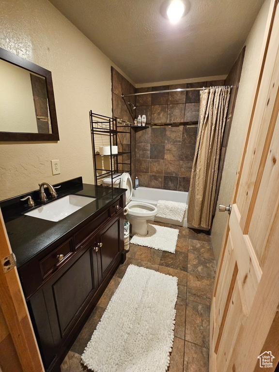 Full bathroom with shower / bath combination with curtain, vanity, toilet, and a textured ceiling