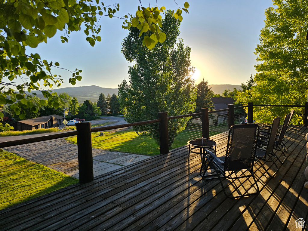 Deck at dusk featuring a mountain view, a yard, and an outdoor fire pit