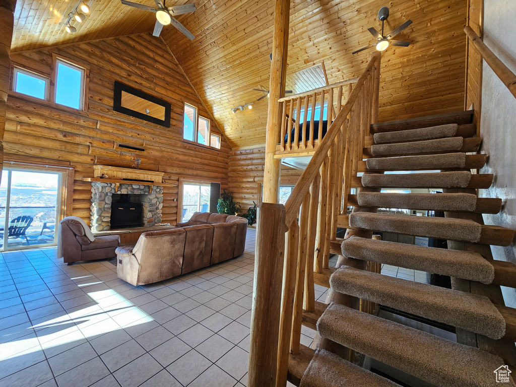 Stairway featuring high vaulted ceiling, rustic walls, ceiling fan, wood ceiling, and tile patterned floors