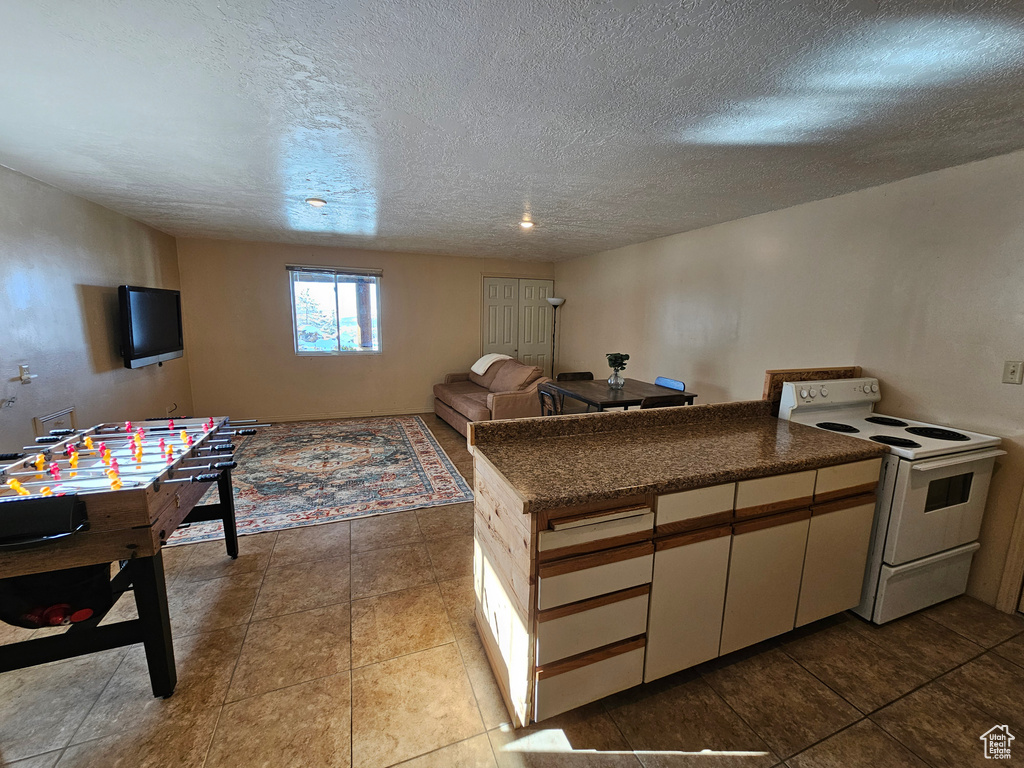 Interior space with tile patterned floors, white electric range, and a textured ceiling