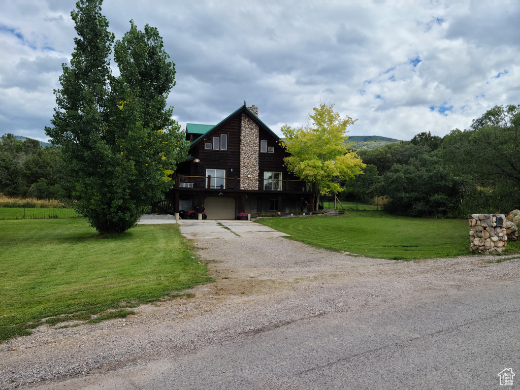 Log home with a wooden deck, a garage, and a front lawn