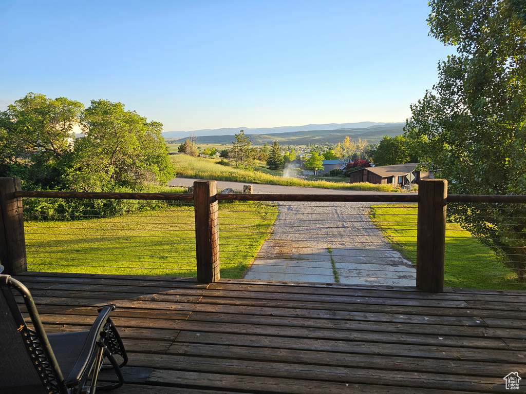 View of community featuring a deck with mountain view and a lawn