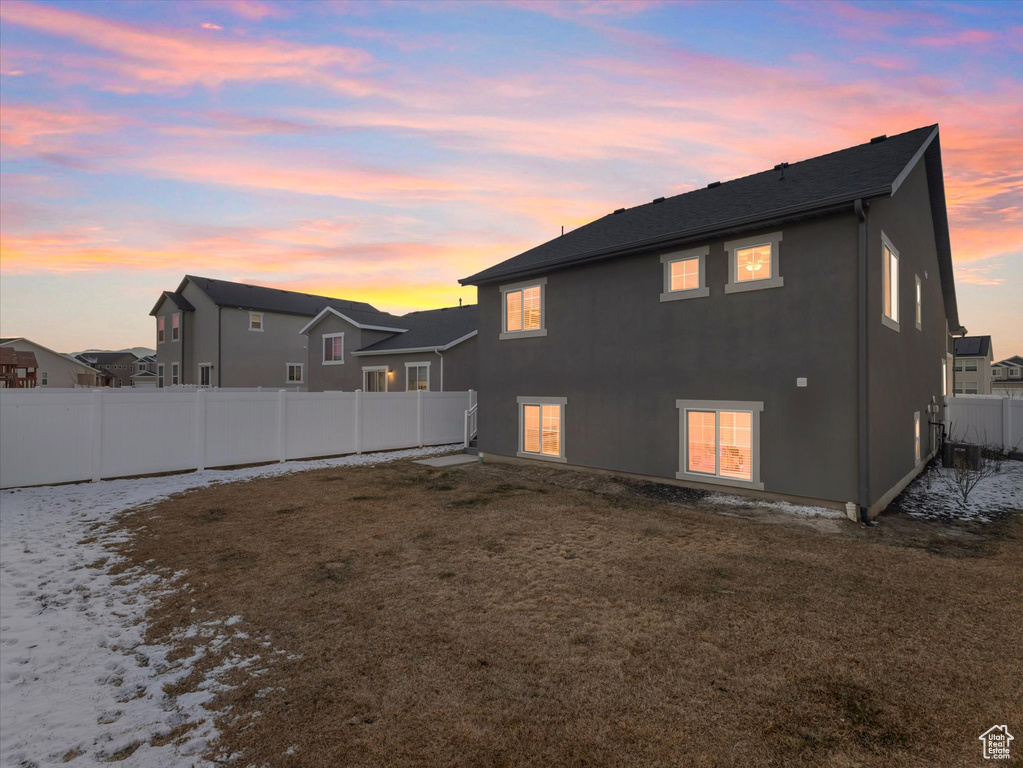 Back house at dusk with a yard