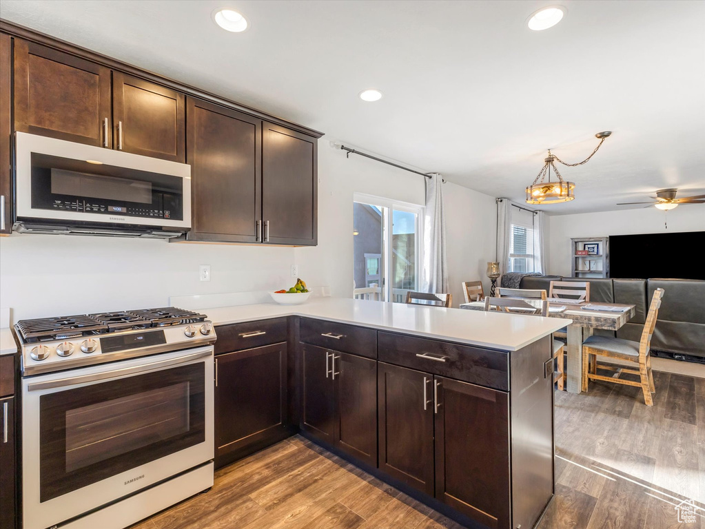 Kitchen featuring dark brown cabinets, light wood-type flooring, kitchen peninsula, and appliances with stainless steel finishes