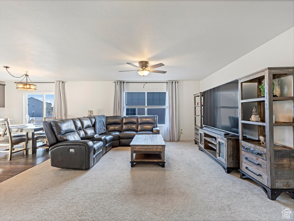 Living room featuring carpet floors and ceiling fan with notable chandelier