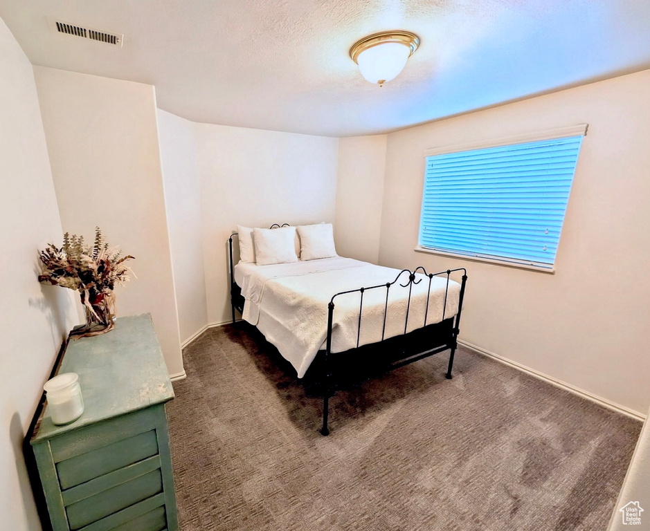 Bedroom with dark carpet and baseboards