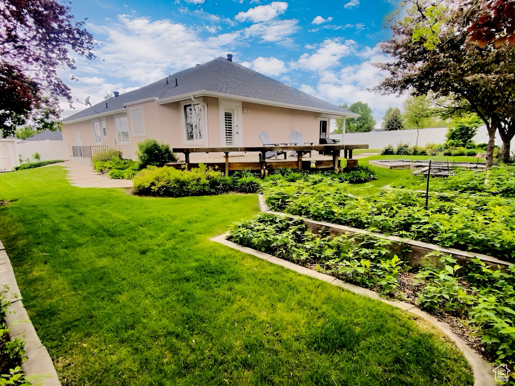 Back of house featuring a garden, stucco siding, and a deck