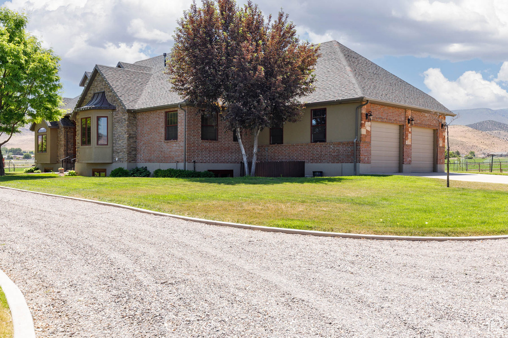 View of front of house featuring brick siding, a shingled roof, an attached garage, driveway, and a mountain view
