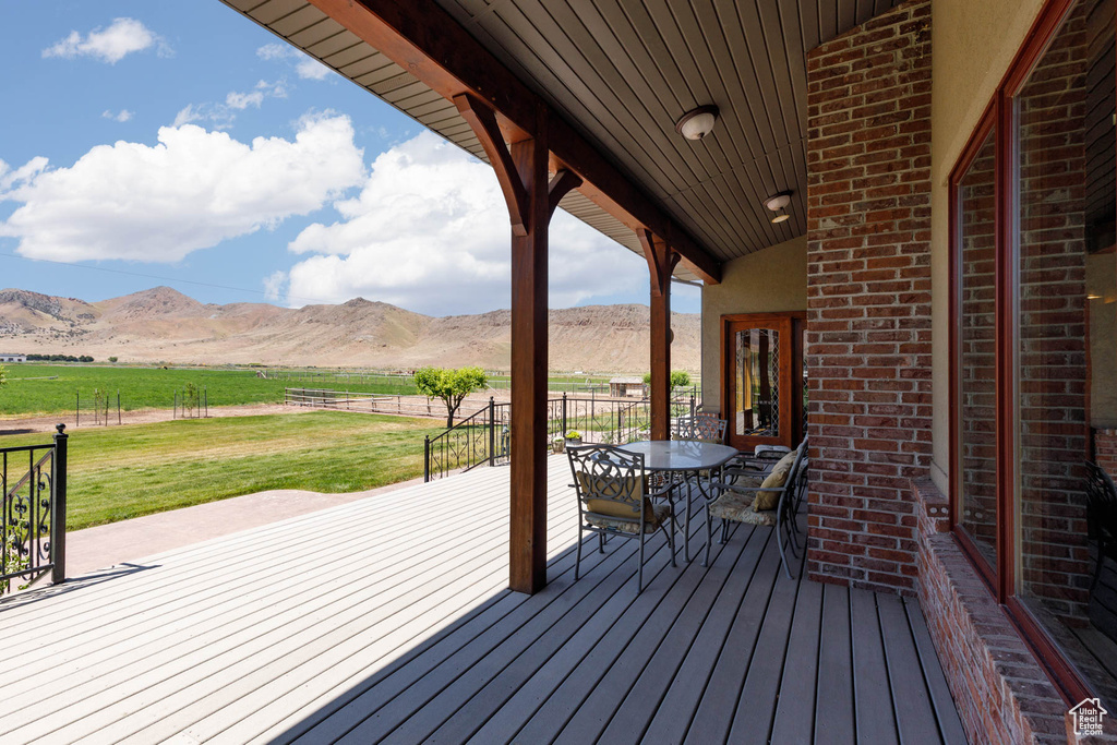 Deck featuring a mountain view, a rural view, a lawn, and outdoor dining space