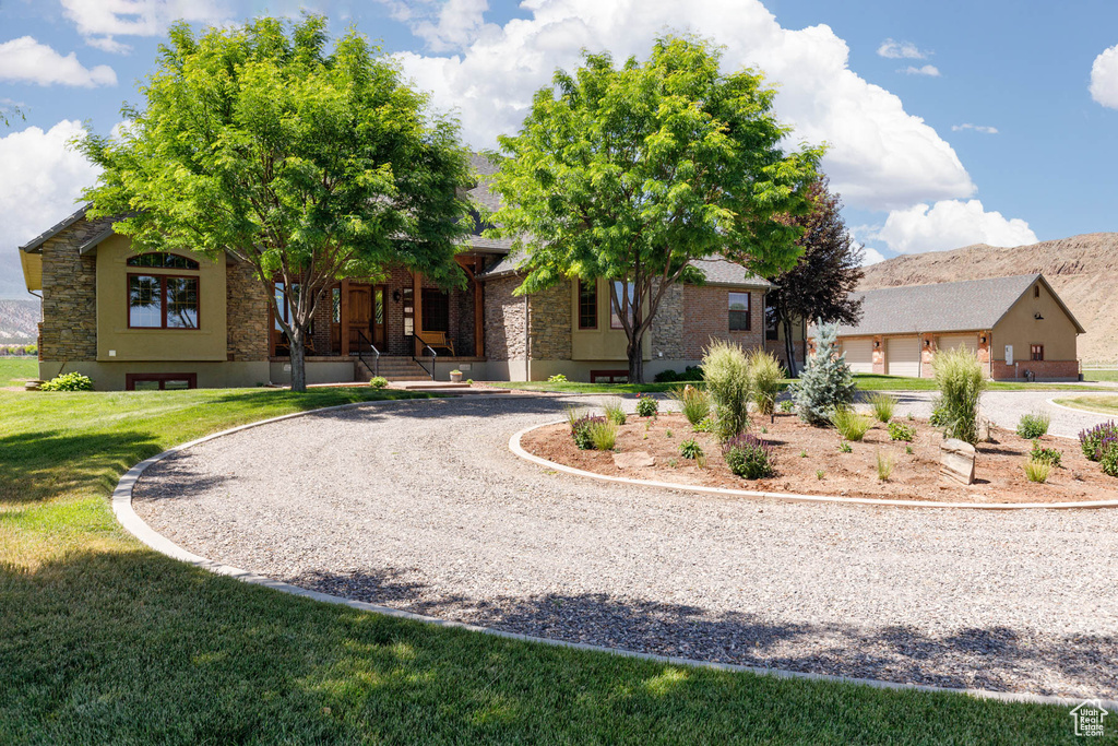 View of front of house featuring curved driveway, stone siding, a front yard, and a porch