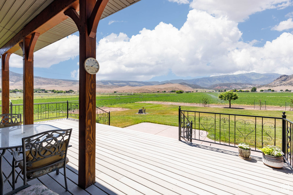 Wooden terrace with a rural view, a lawn, and a mountain view