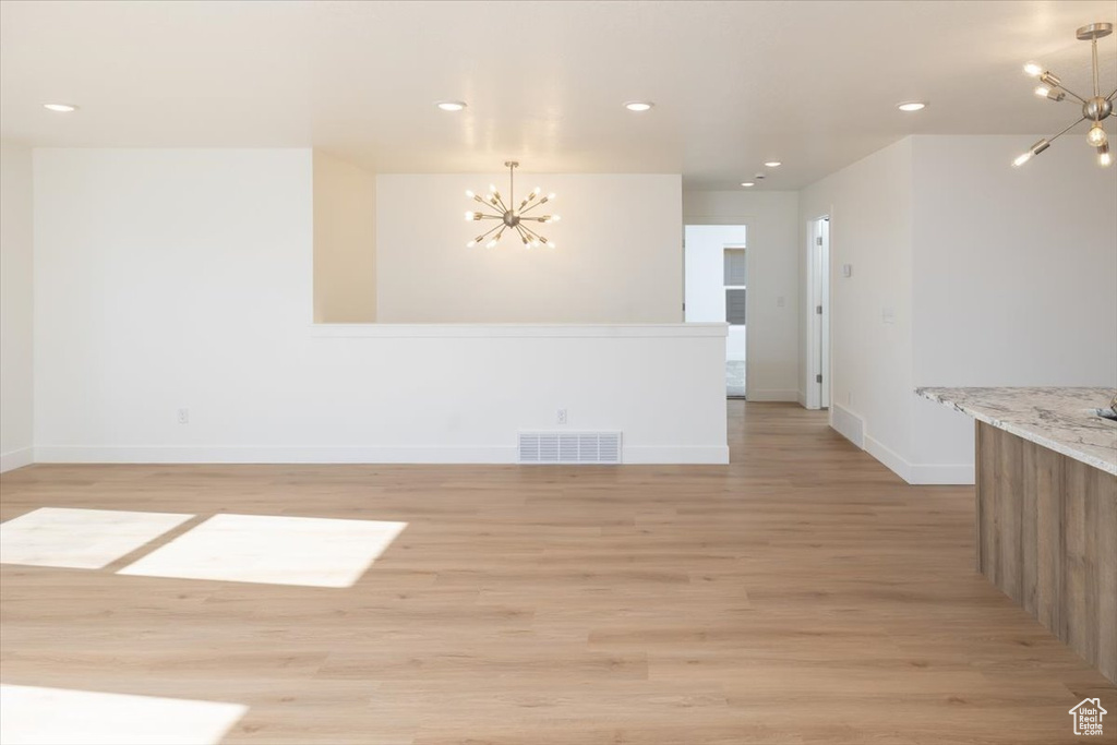 Empty room featuring a chandelier and light wood-type flooring