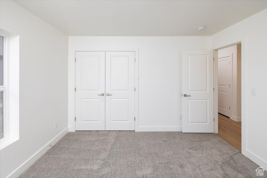 Unfurnished bedroom with light colored carpet and a closet