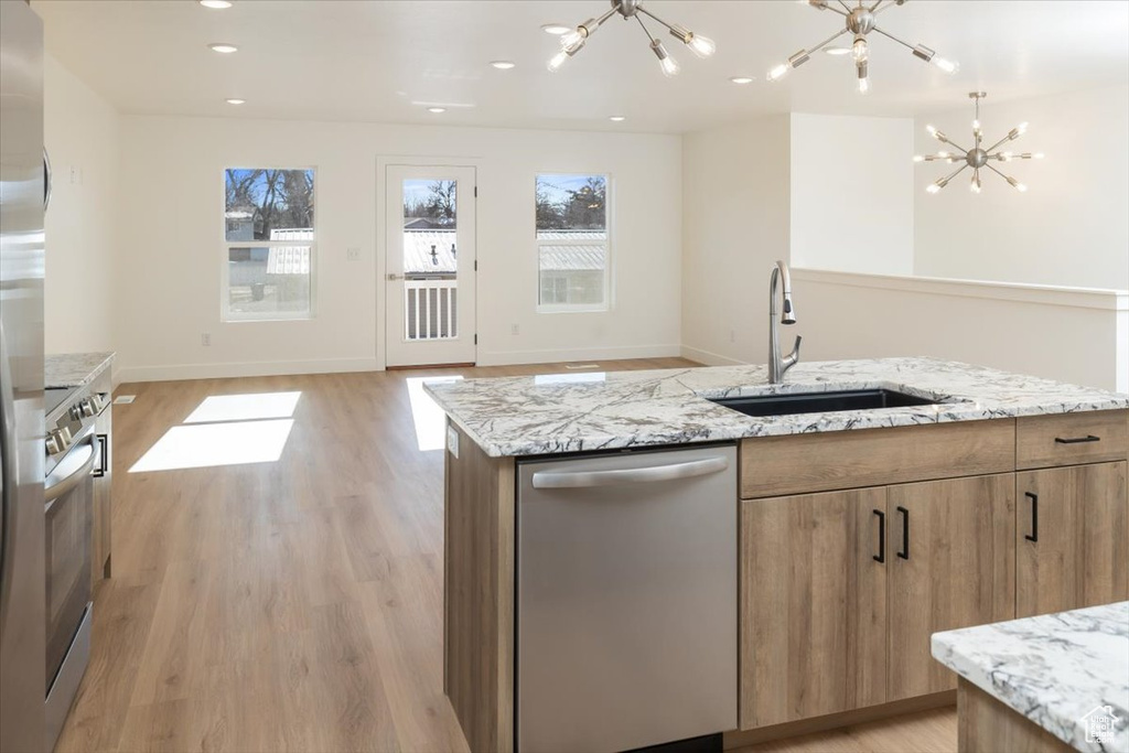 Kitchen featuring dishwasher, sink, a kitchen island with sink, a notable chandelier, and light hardwood / wood-style floors