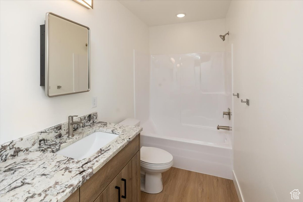 Full bathroom with vanity, wood-type flooring, shower / washtub combination, and toilet