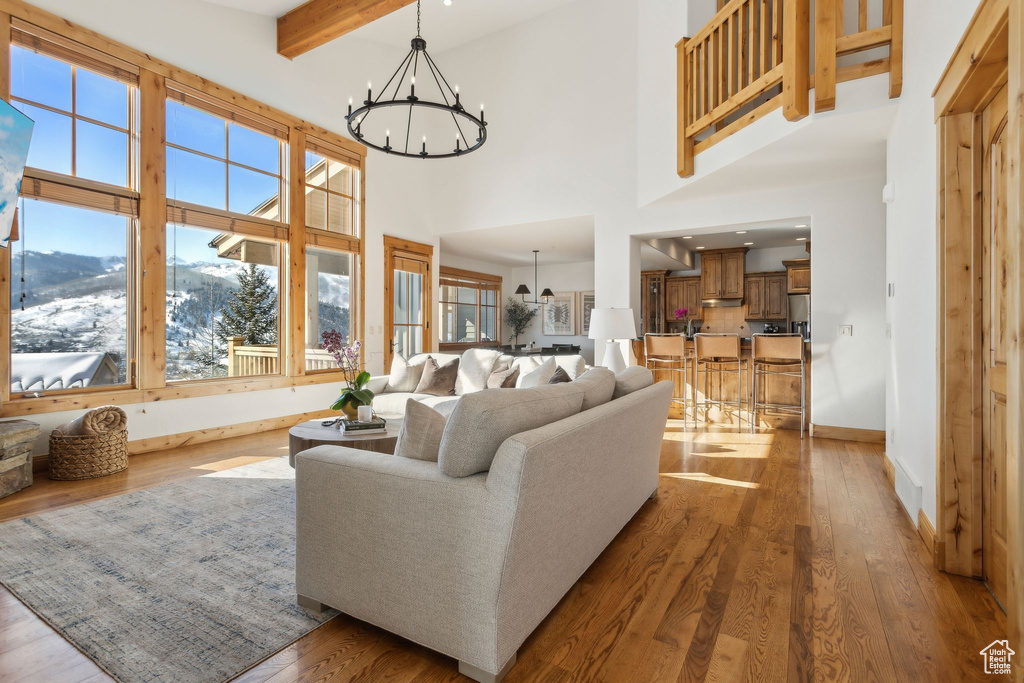 Living room with a high ceiling, hardwood / wood-style flooring, a chandelier, and beam ceiling