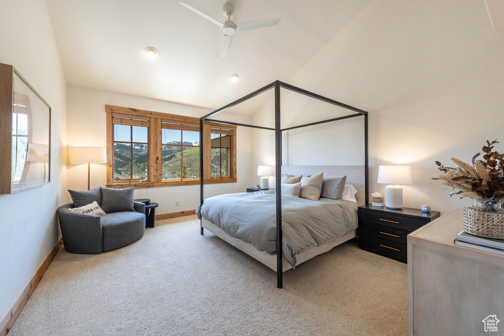 Bedroom with vaulted ceiling, light colored carpet, baseboards, and a ceiling fan
