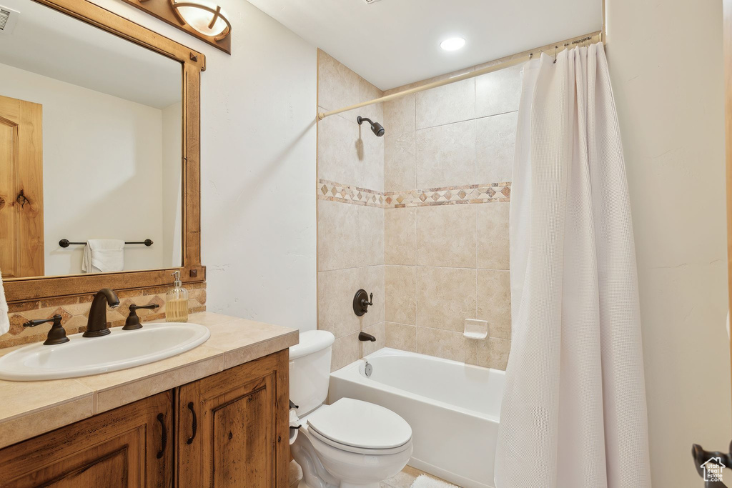 Full bathroom with vanity, backsplash, shower / bath combo, and toilet