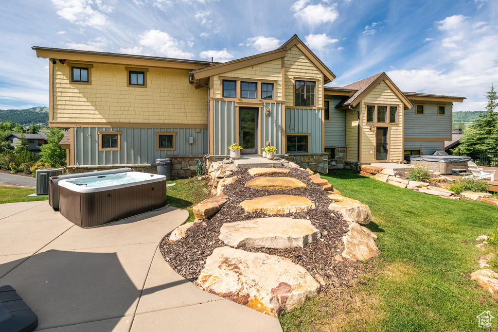 Back of property featuring a yard, central AC, and a hot tub