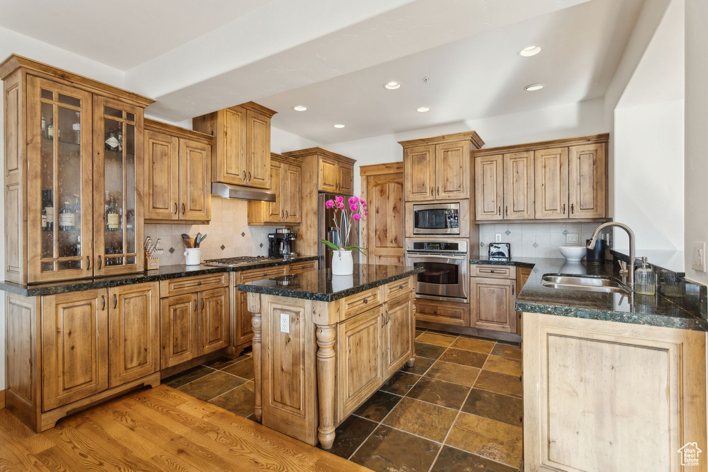 Kitchen featuring stainless steel appliances, tasteful backsplash, a center island, and sink