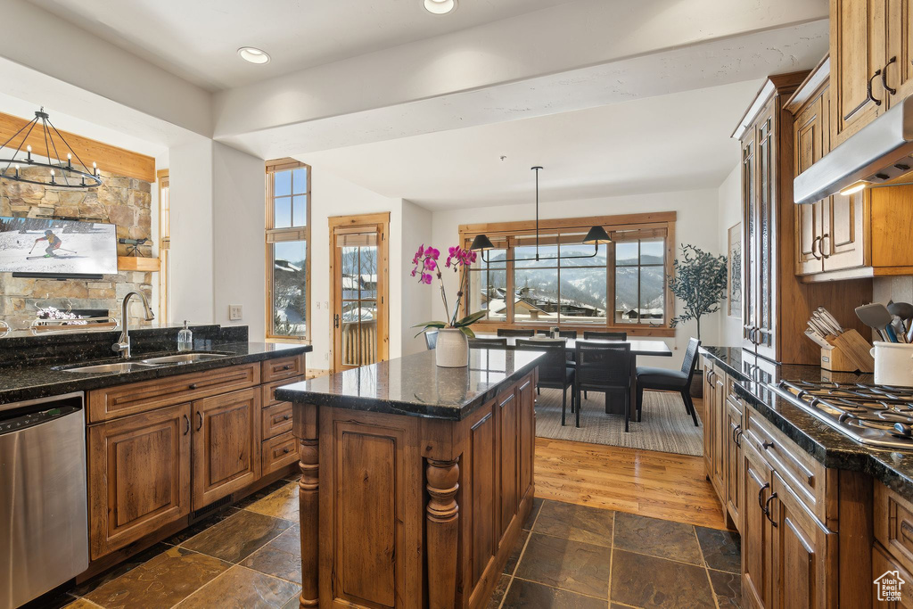 Kitchen with sink, a chandelier, appliances with stainless steel finishes, a kitchen island, and pendant lighting